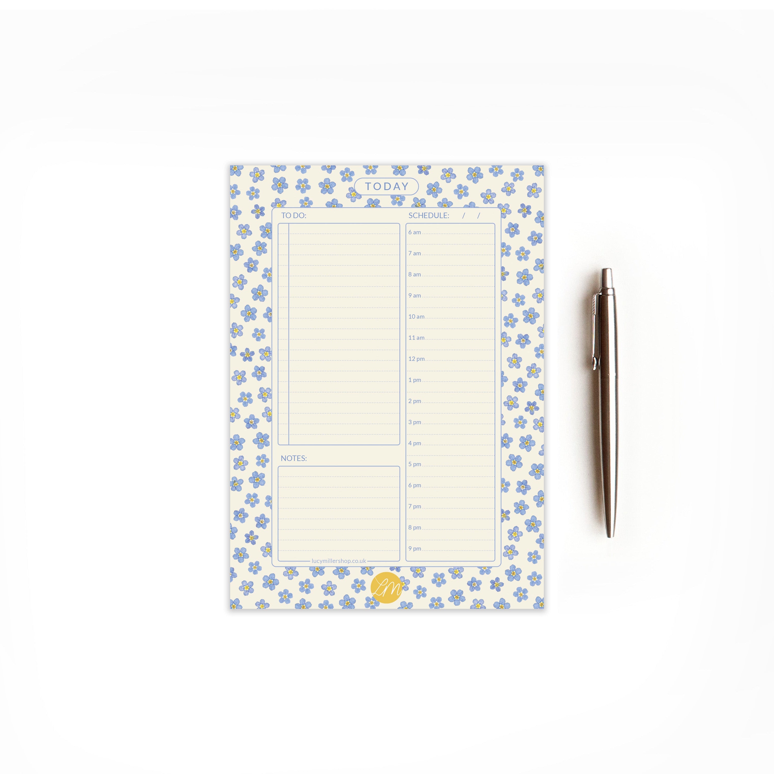 Floral daily planner pad with a pressed forget-me-not design. On a white background and styled with a pen.