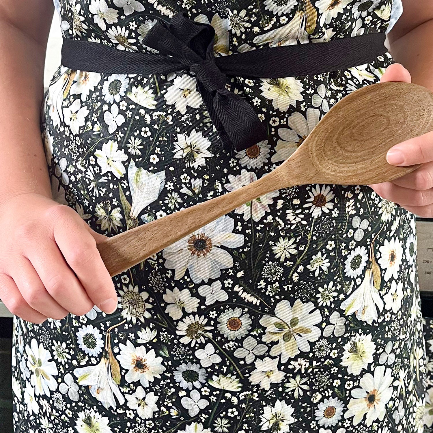 Botanical Apron with a pressed flower design in black and white, with adjustable neck, and long black ties.