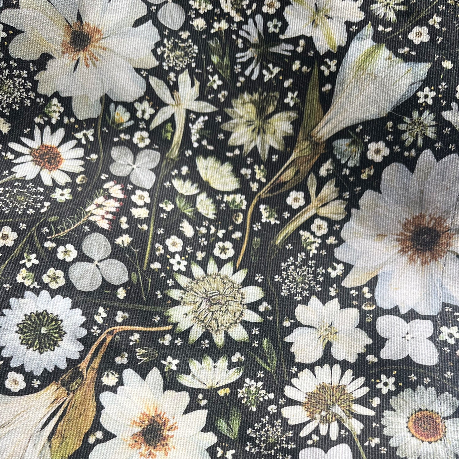 Nature-inspired apron made from cotton. Featuring a floral design of white flowers on a black background. Flowers include Anemone, Nigella, Daisy, Astrantia, Heather, Hydrangea and Queen Anne’s Lace.