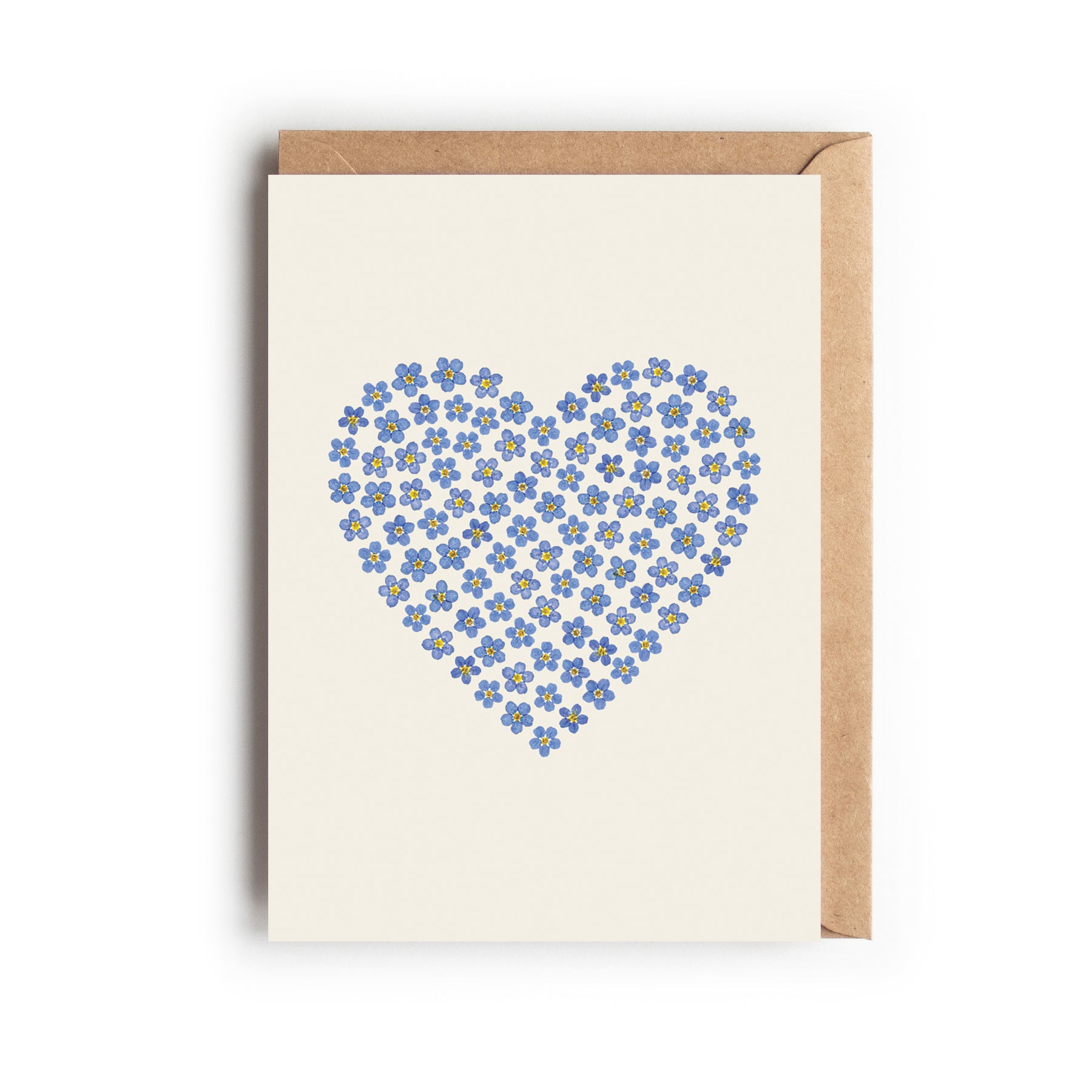Card with a heart made of pressed blue forget-me-not flowers on an off-white background. Designed and made in the UK.