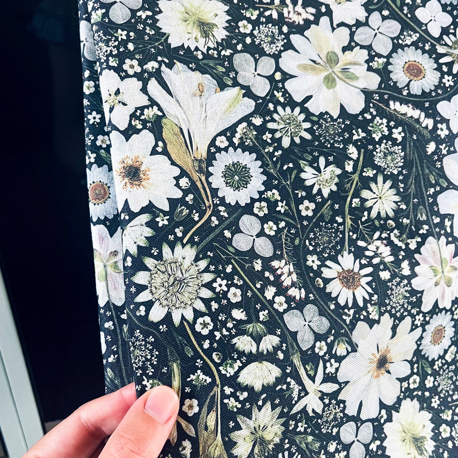 Close up of a floral cotton tea towel with a pressed flower design in black and white. Flowers include Anemone, Nigella, Astrantia, Hydrangea, Daisy, Cow Parsley and Heather.