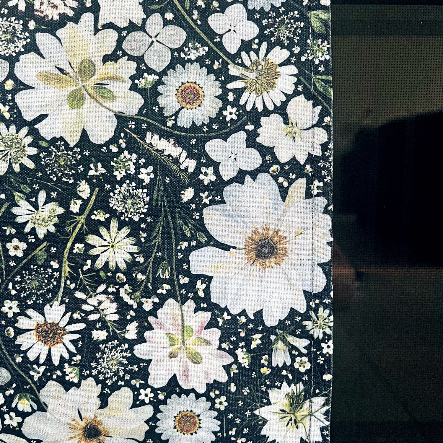 Close up of a pretty floral tea towel, featuring a pressed flower design in black and white. Flowers include Anemone, Nigella, Astrantia, Hydrangea, Daisy, Cow Parsley and Heather.