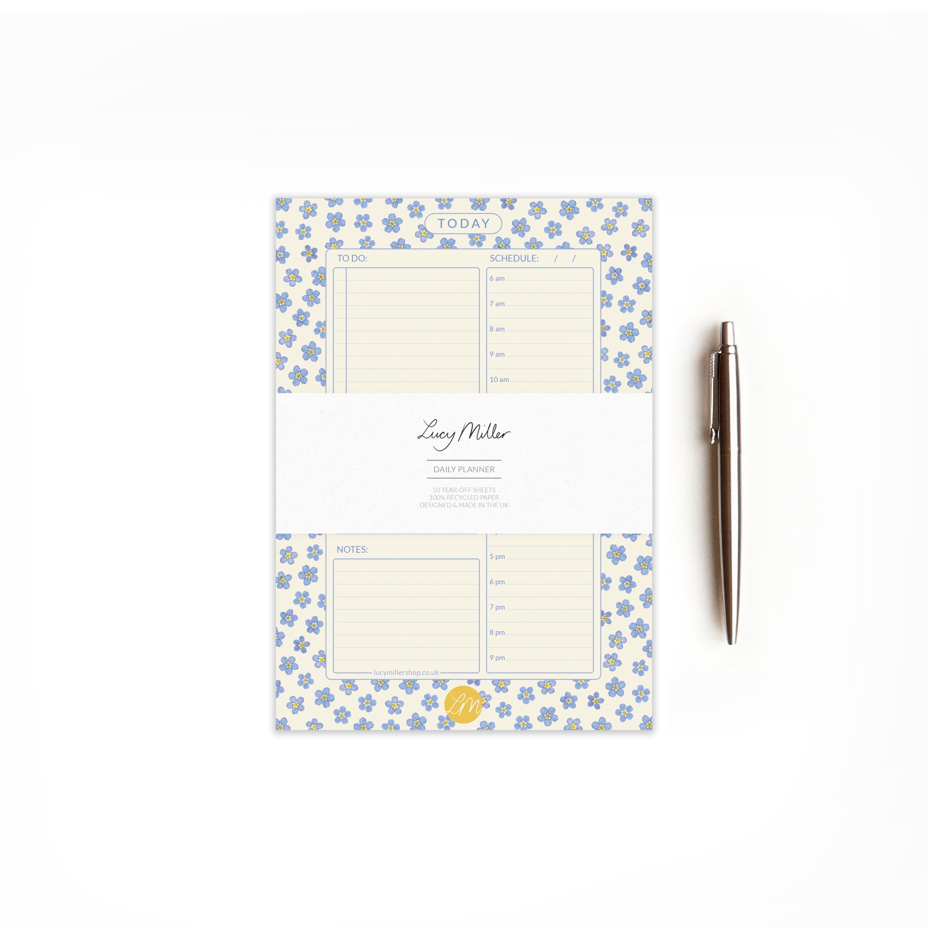 Pressed forget-me-not daily planner pad with branded 'Lucy Miller' belly band, on a white background and styled with a pen.
