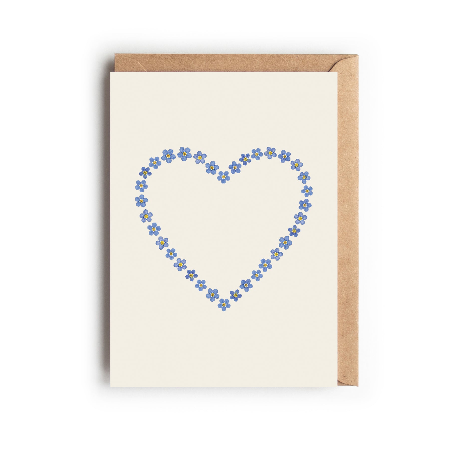 Card with a love heart made of pressed blue forget-me-not flowers on an off-white background. Designed and made in the UK.